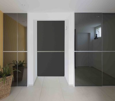 Edel gestalteter Einbauschrank mit grau-verspiegelten Schiebetüren als Fronten und passender Durchgangstüre dazwischen